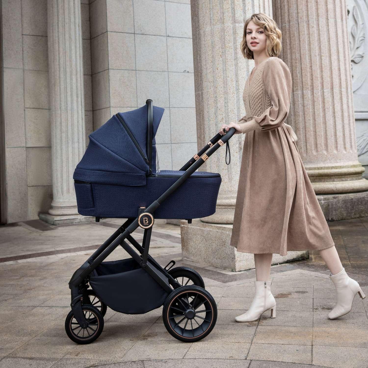 Woman pushing a Babymore Chia stroller with carrycot in Midnight Blue colour