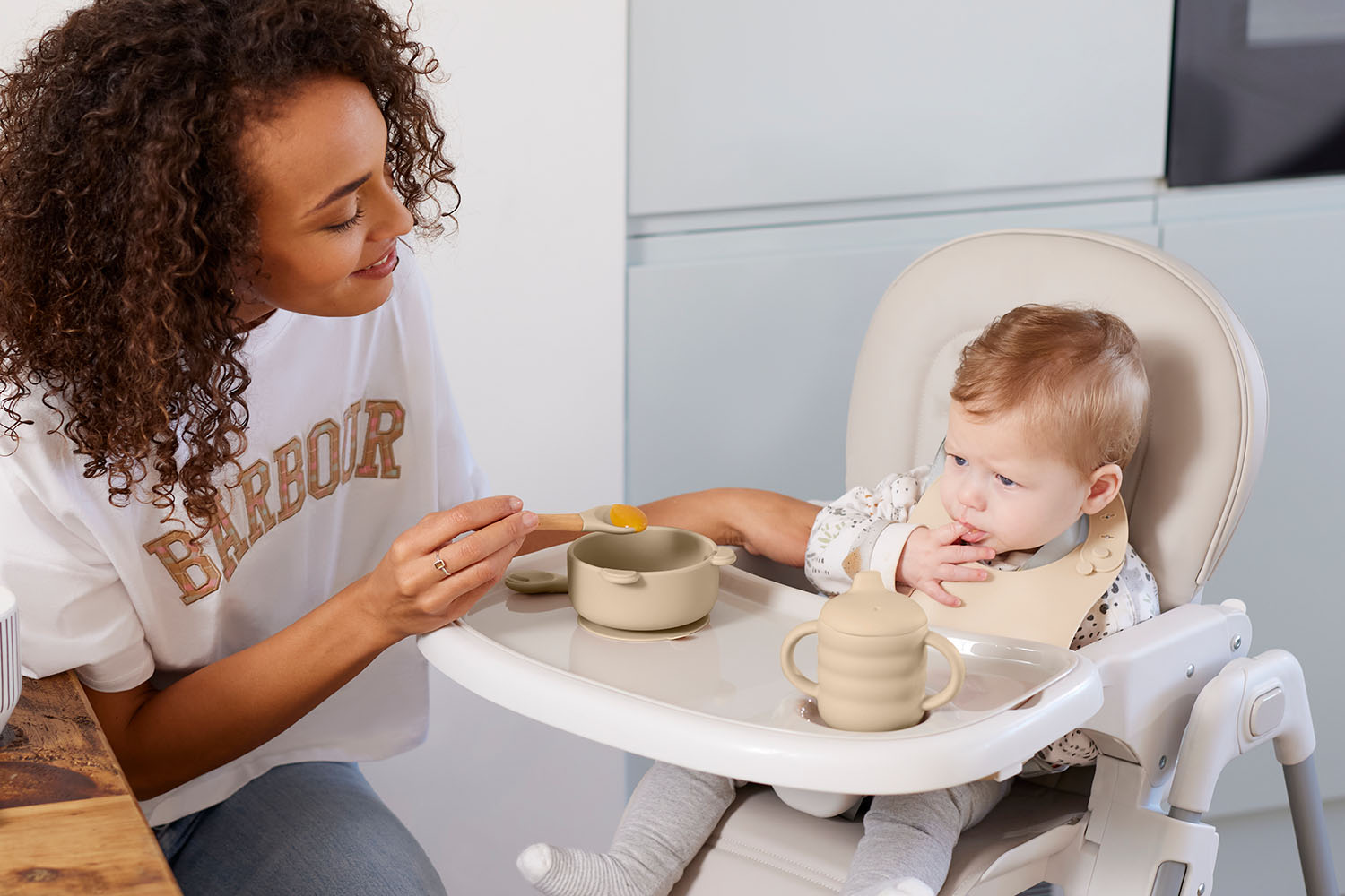 Mom feeding her baby using Ickle Bubba 6-Piece Silicone Baby Feeding Set in Beige colour