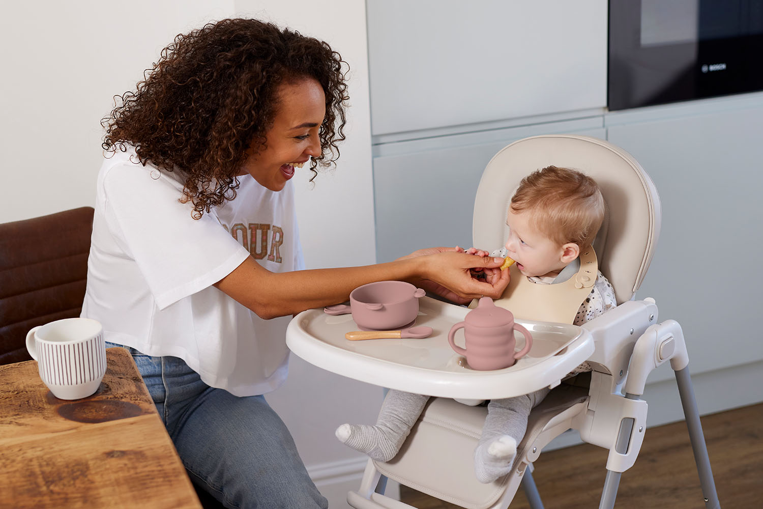 Mom feeding her baby using Ickle Bubba's 6-Piece Silicone Baby Feeding Set in Pink colour