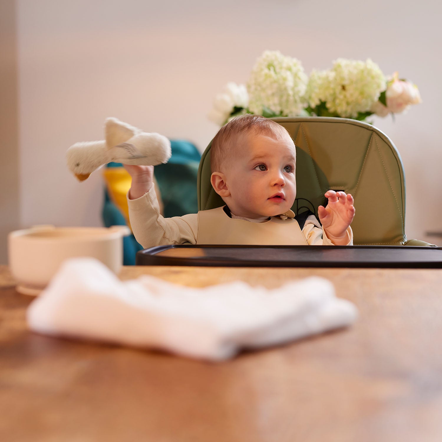 Baby sitting on a Ickle Bubba Flip Magic Fold Highchair in Sage Green colour