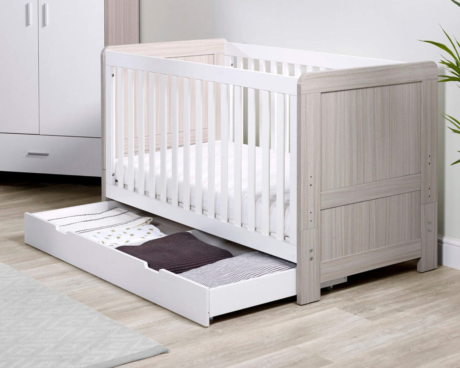 Ickle Bubba Pembrey 2-in-1 Cot Bed in Ash Grey and White colour with opened under drawer with baby clothes and beddings