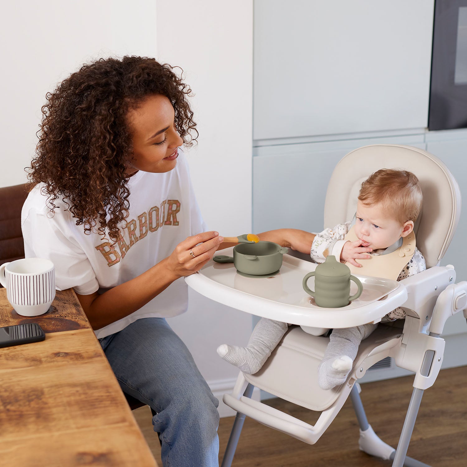 Mom serving baby food to her bubba sitting in Ickle Bubba Switch Multi Function Highchair