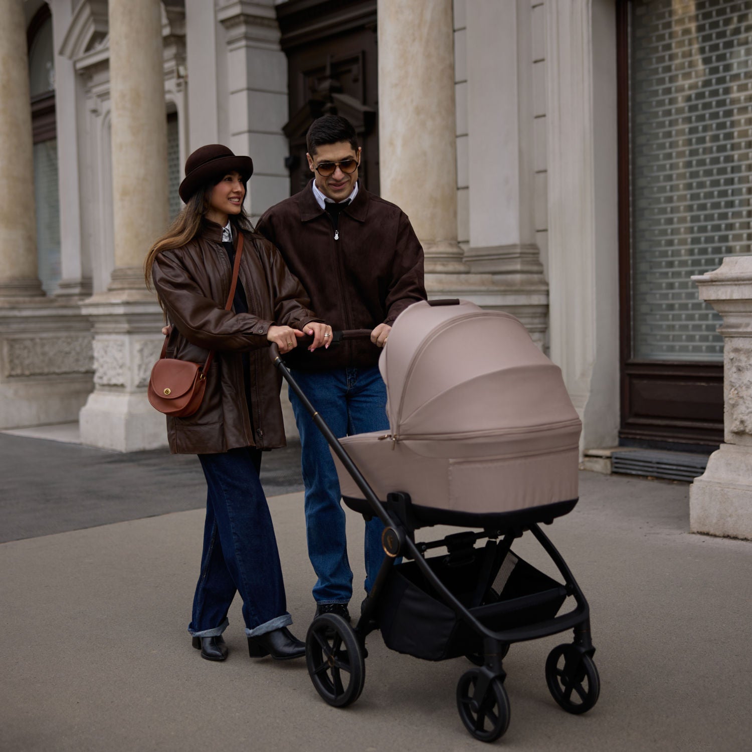A couple walking and pushing a Venicci Claro 2-in-1 Pram in Almond colour