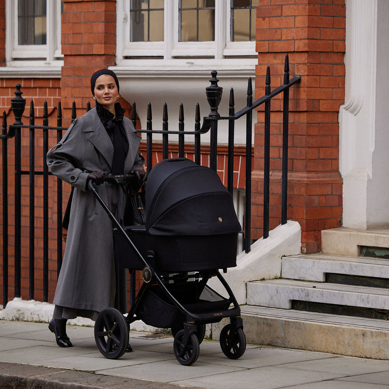 A mother walking and pushing a Venicci Upline 2 Pram in All Black colour